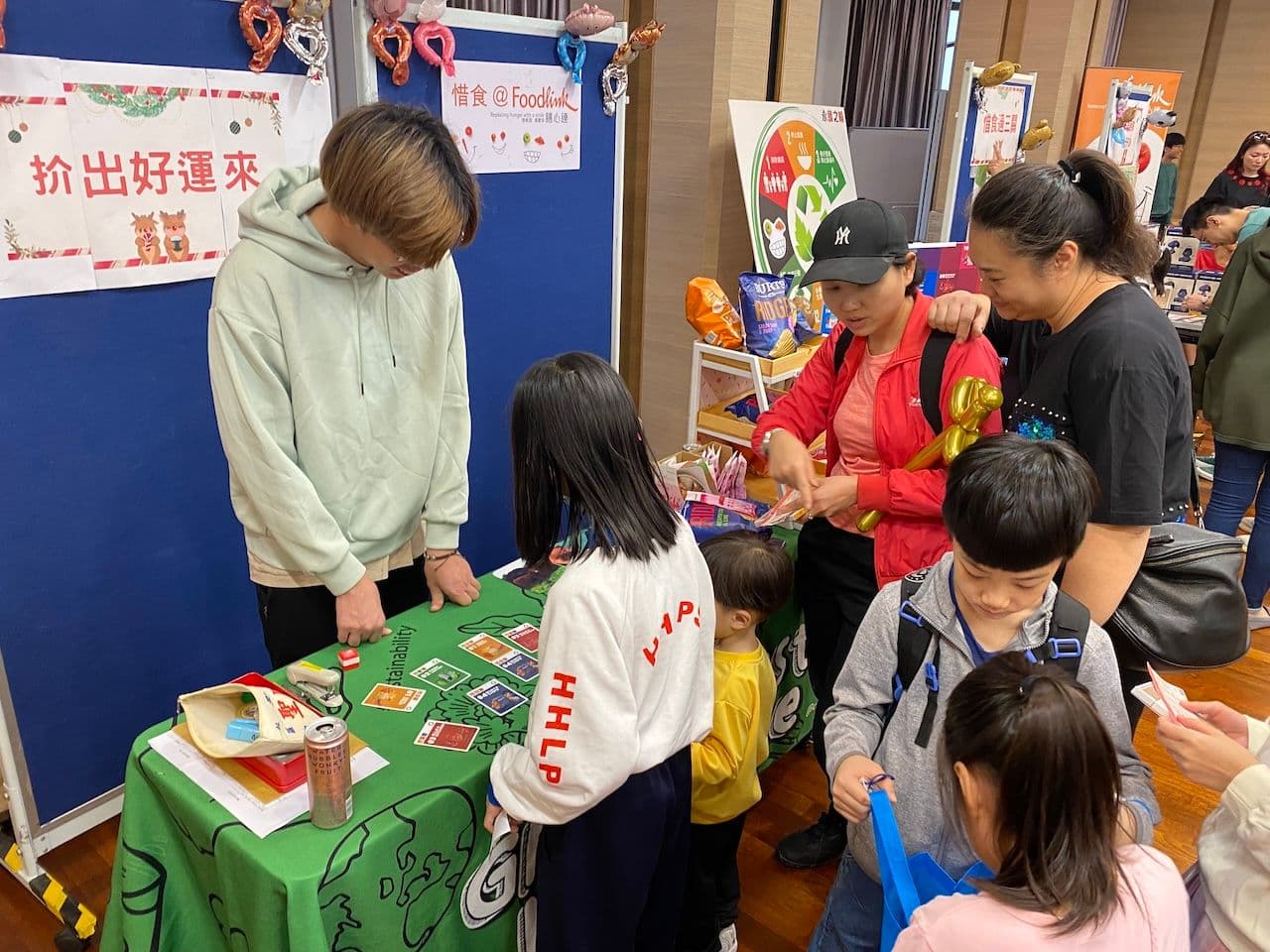 A busy booth with children and families around a table of activities and games at the Foodlink Christmas bazaar in December 2023