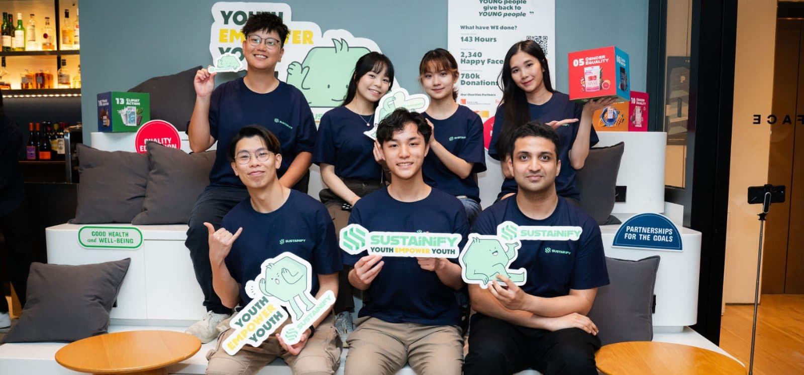 The Sustainify team seated together in a lounge, holding Sustainify signs