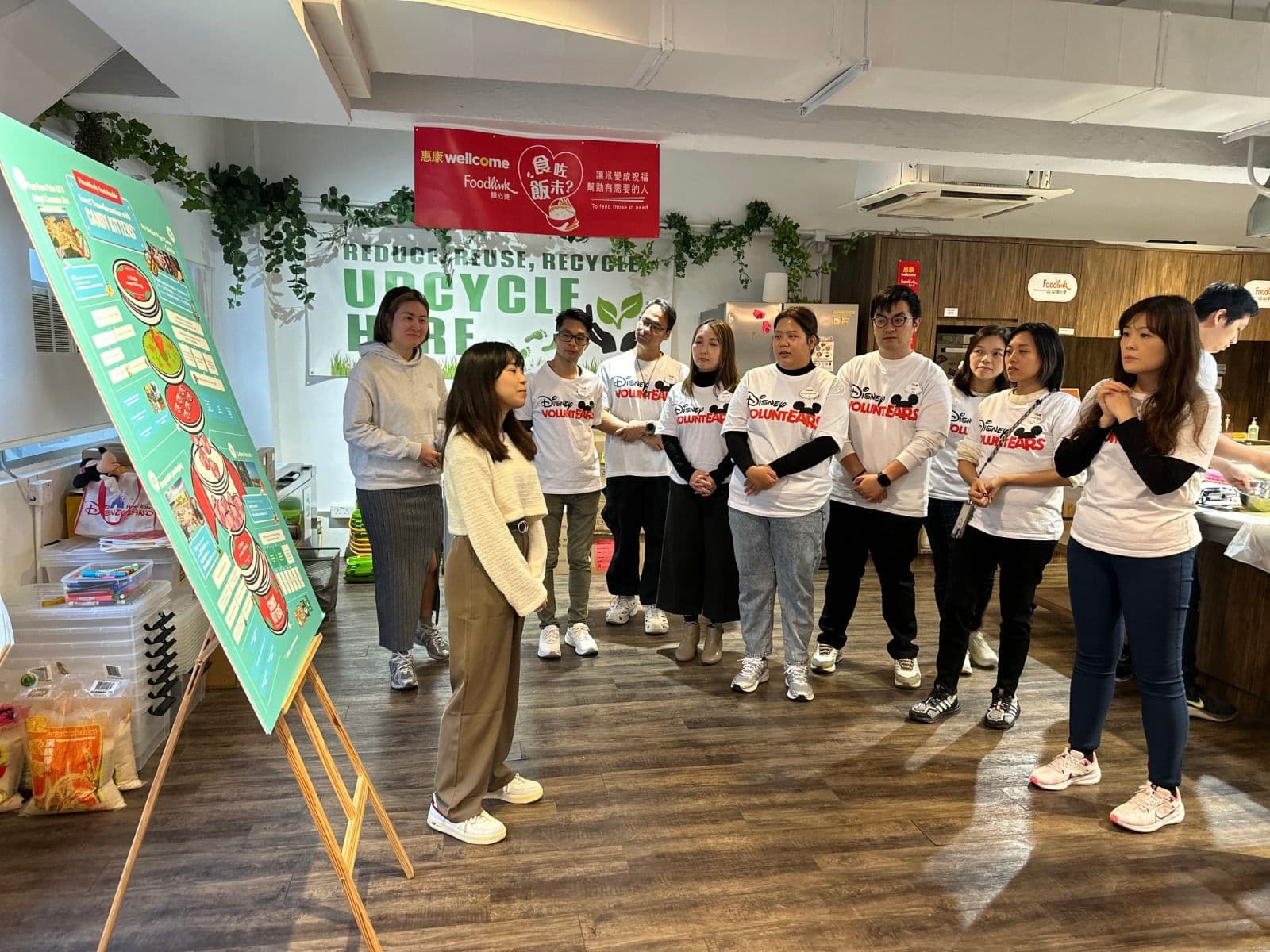 Volunteers standing together at a Foodlink upcycling activity, in front of a wall reading "Reduce, Reuse, Recycle, Upcycle here"